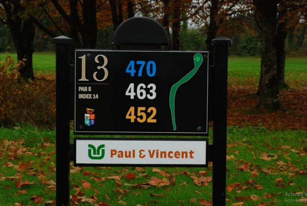 Golf hole 13 sign with yardage, surrounded by autumn leaves and trees. Paul & Vincent sign below.